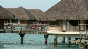 Men Walk Along Deck Near Huts at Bora Bora Resort